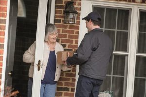 elderly female receiving medical supplies at home from delivery man